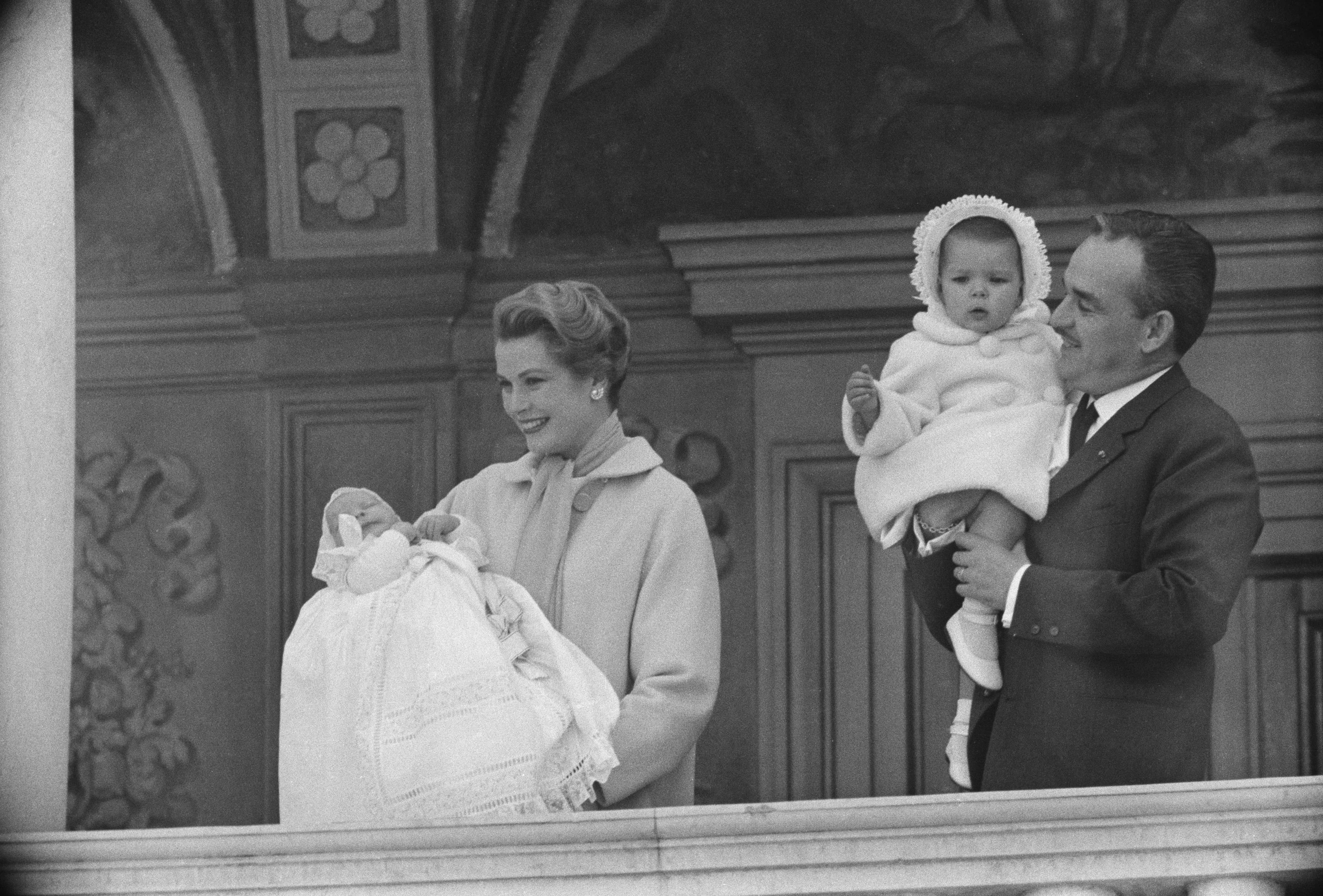 Rainier III, Prince of Monaco (1923 - 2005), holds Caroline, Princess of Hanover, while wife, American actress Grace Kelly, Princess of Monaco (1929 - 1982), presents Prince Albert II from the balcony of the Prince's Palace of Monaco, April 1958. (Photo by Daily Express/Getty Images)