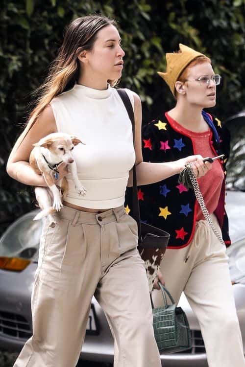 Tallulah wore a faded red t-shirt beneath a black cardigan adorned with multi-colored stars, while Scout chose a monochromatic ensemble consisting of a white sleeveless shirt with a high neckline and a pair of beige trousers (Backgrid)