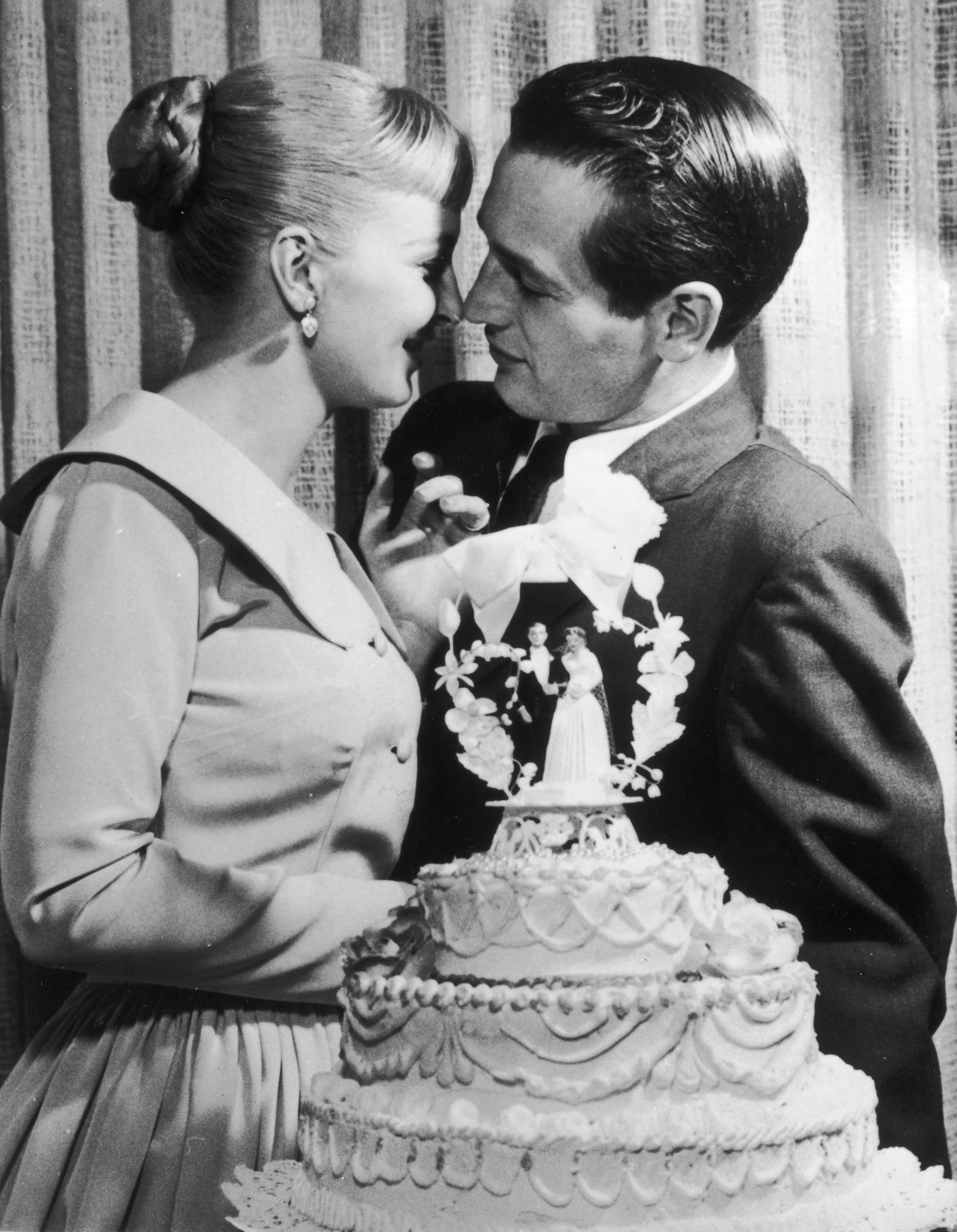 American actors and newlyweds Paul Newman and Joanne Woodward kiss behind a wedding cake during their wedding reception at the El Rancho hotel-casino, Las Vegas, Nevada, January 29, 1958. (Photo by Hulton Archive/Getty Images)