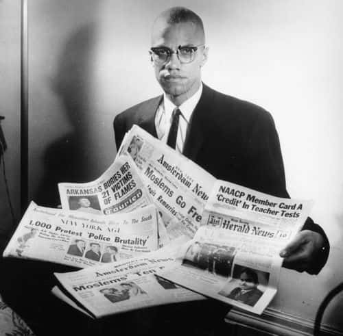 Portrait of human rights activist Malcolm X reading stories about himself in a pile of newspapers, circa 1963. (Photo by Three Lions/Hulton Archive/Getty Images)