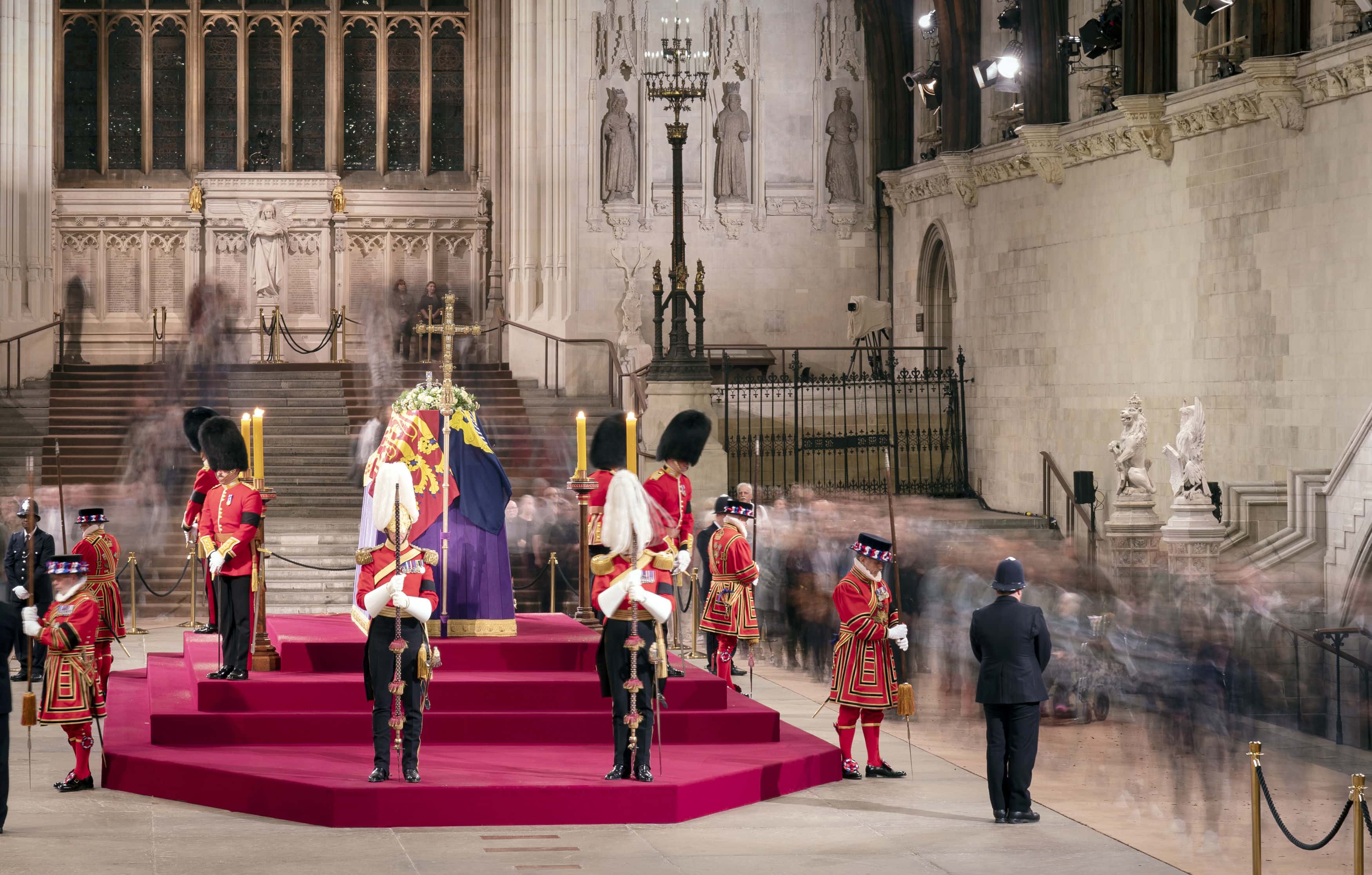 A long exposure photograph showing members of the public as they file past the coffin of Queen Elizabeth II, draped in the Royal Standard with the Imperial State Crown and the Sovereign's orb and sceptre, lying in state on the catafalque in Westminster Hall at the Palace of Westminster on September 15, 2022 in London, England. Members of the public are able to pay respects to Her Majesty Queen Elizabeth II for 23 hours a day from 17:00 on September 14, 2022 until 06:30 on September 19, 2022. Queen Elizabeth II died at Balmoral Castle in Scotland on September 8, 2022, and is succeeded by her eldest son, King Charles III. (Photo by Danny Lawson - WPA Pool/Getty Images)