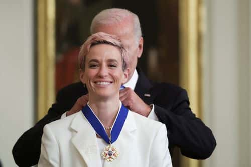 U.S. President Joe Biden presents the Presidential Medal of Freedom to Megan Rapinoe, soccer player and advocate for gender pay equality, during a ceremony in the East Room of the White House July 7, 2022 in Washington, DC. President Biden awarded the nation's highest civilian honor to 17 recipients. The award honors individuals who have made exemplary contributions to the prosperity, values, or security of the United States, world peace, or other significant societal, public or private endeavors.