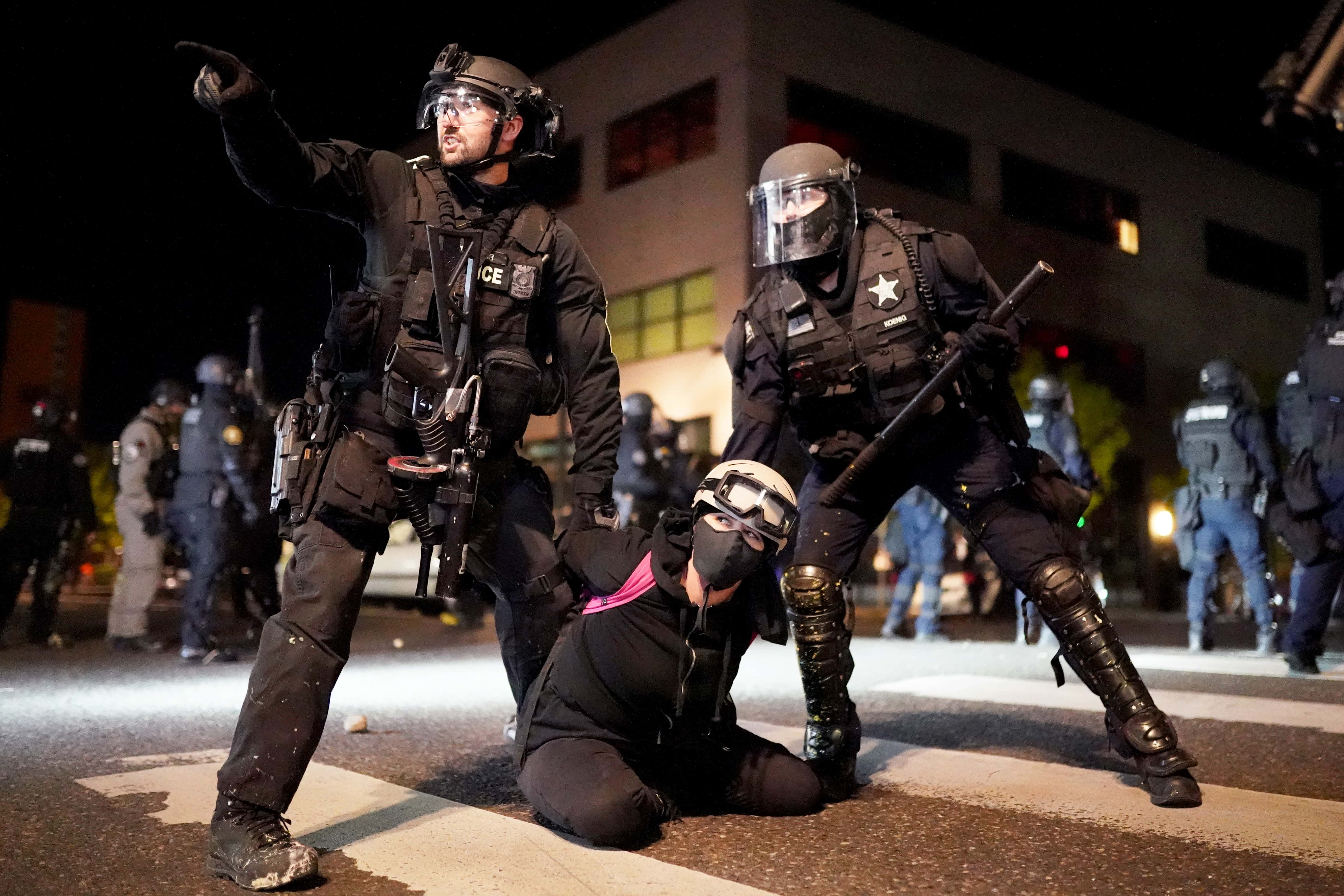 Portland police and Oregon State Patrol officers work together to arrest a protester in front of the Portland Police Bureau North Precinct on the 75th day of protests against racial injustice and police brutality on August 11, 2020 in Portland, Oregon. Crowd sizes began growing again last week as protesters regularly march on city and county law enforcement buildings.