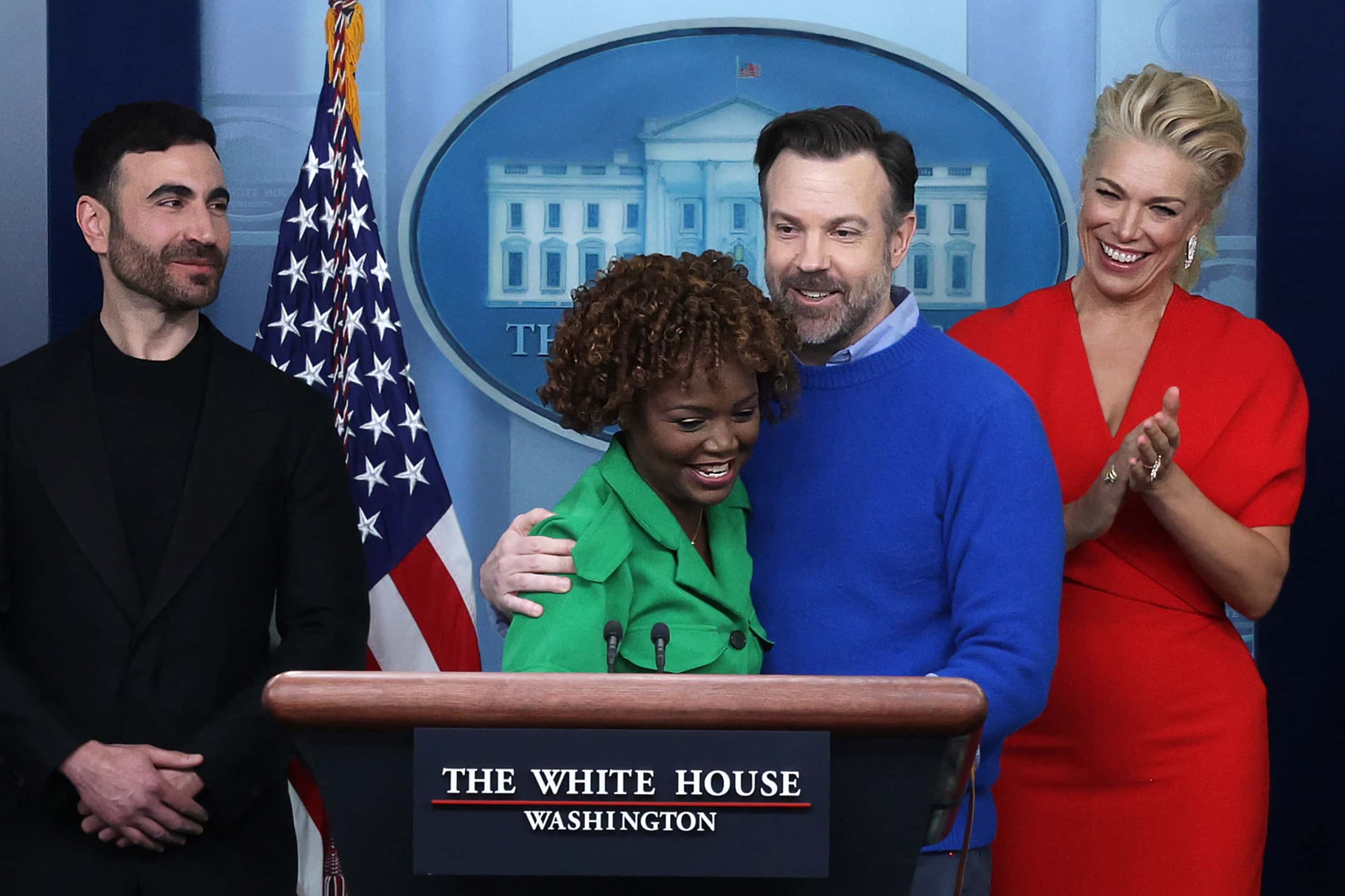 Comedian Jason Sudeikis of the Apple TV+ comedy series Ted Lasso embraces White House Press Secretary Karine Jean-Pierre as other cast members Brett Goldstein (L) and Hannah Waddingham look on during a White House daily news briefing at the James S. Brady Press Briefing Room on March 20, 2023, in Washington, DC. (Alex Wong/Getty Images)
