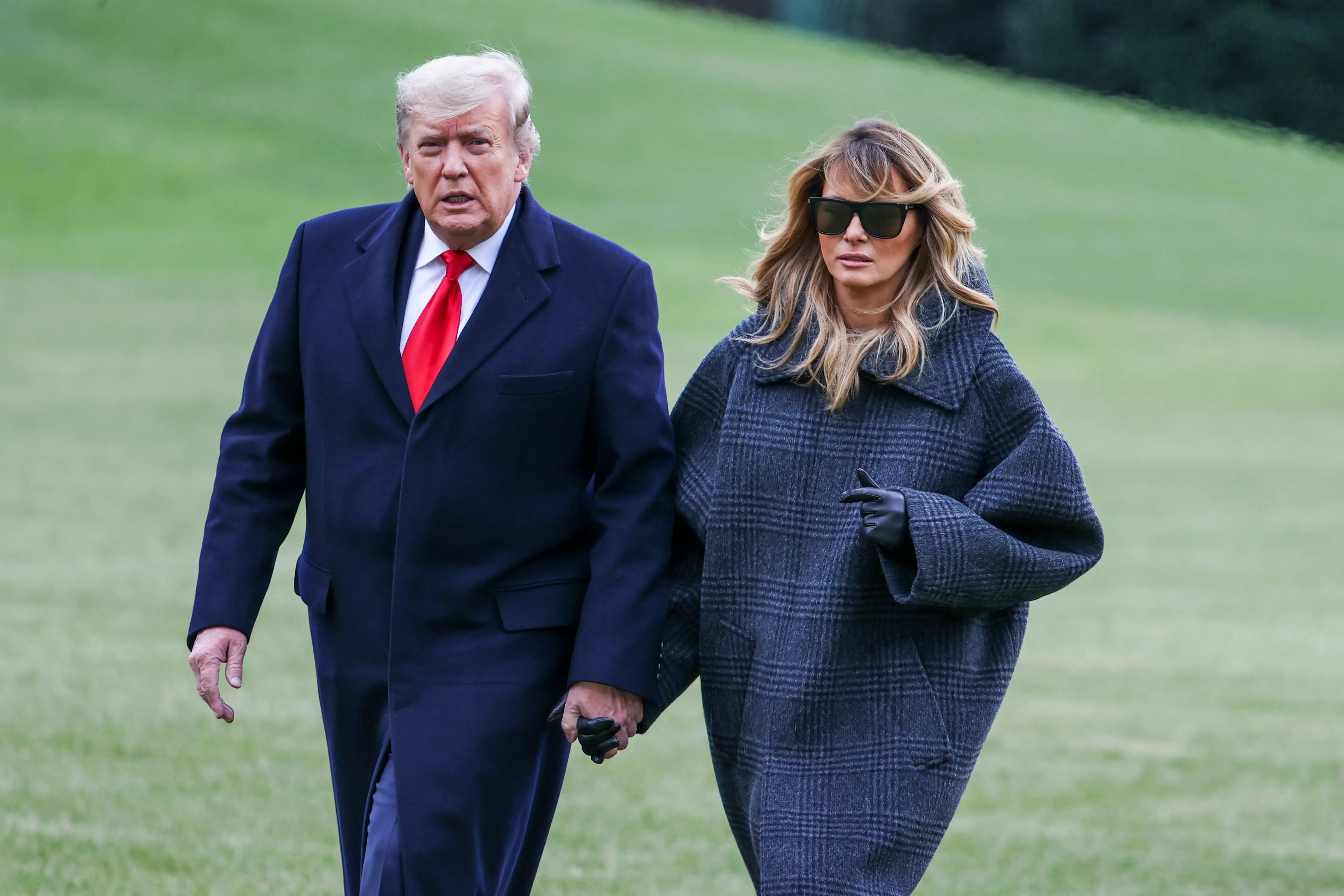U.S. President Donald Trump and First Lady Melania Trump walk on the South Lawn while returning to the White House on December 31, 2020 in Washington, DC. President Trump and the First Lady returned to Washington, DC early and will not be in attendance at the annual New Years Eve party at his Mar-a-Lago home in Palm Beach. (Photo by Tasos Katopodis/Getty Images)