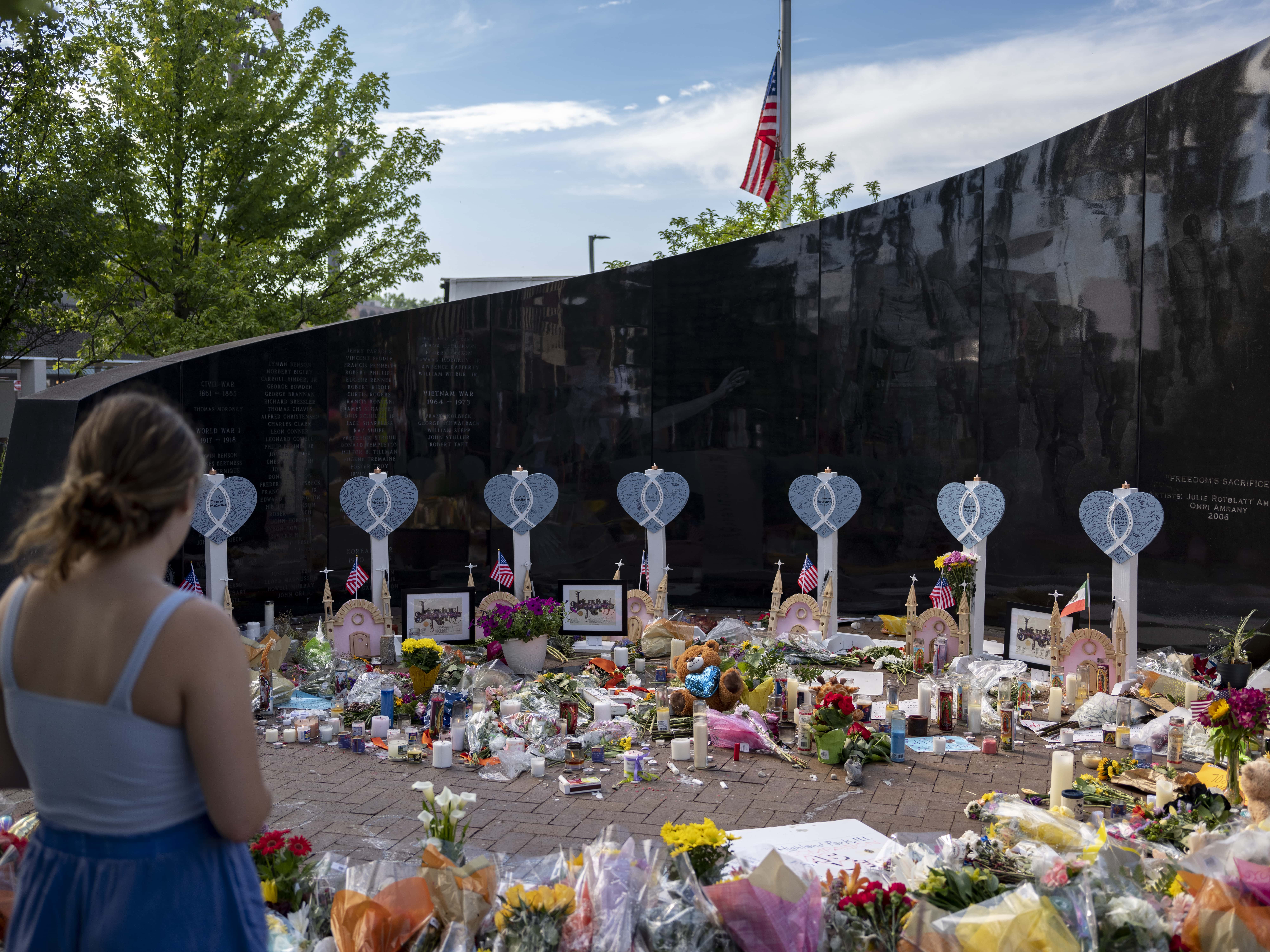 People mourn at memorials placed near the scene of a shooting at a Fourth of July parade, on July 7, 2022 in Highland Park, Illinois. Authorities have charged Robert “Bobby” E. Crimo III, 22, with seven counts of first-degree murder in the attack that also injured 47, according to published reports.