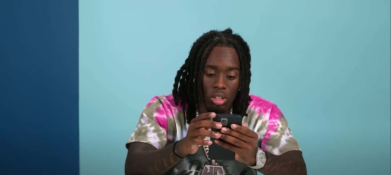 Kai Cenat showing his iPhone (GQ/YouTube)