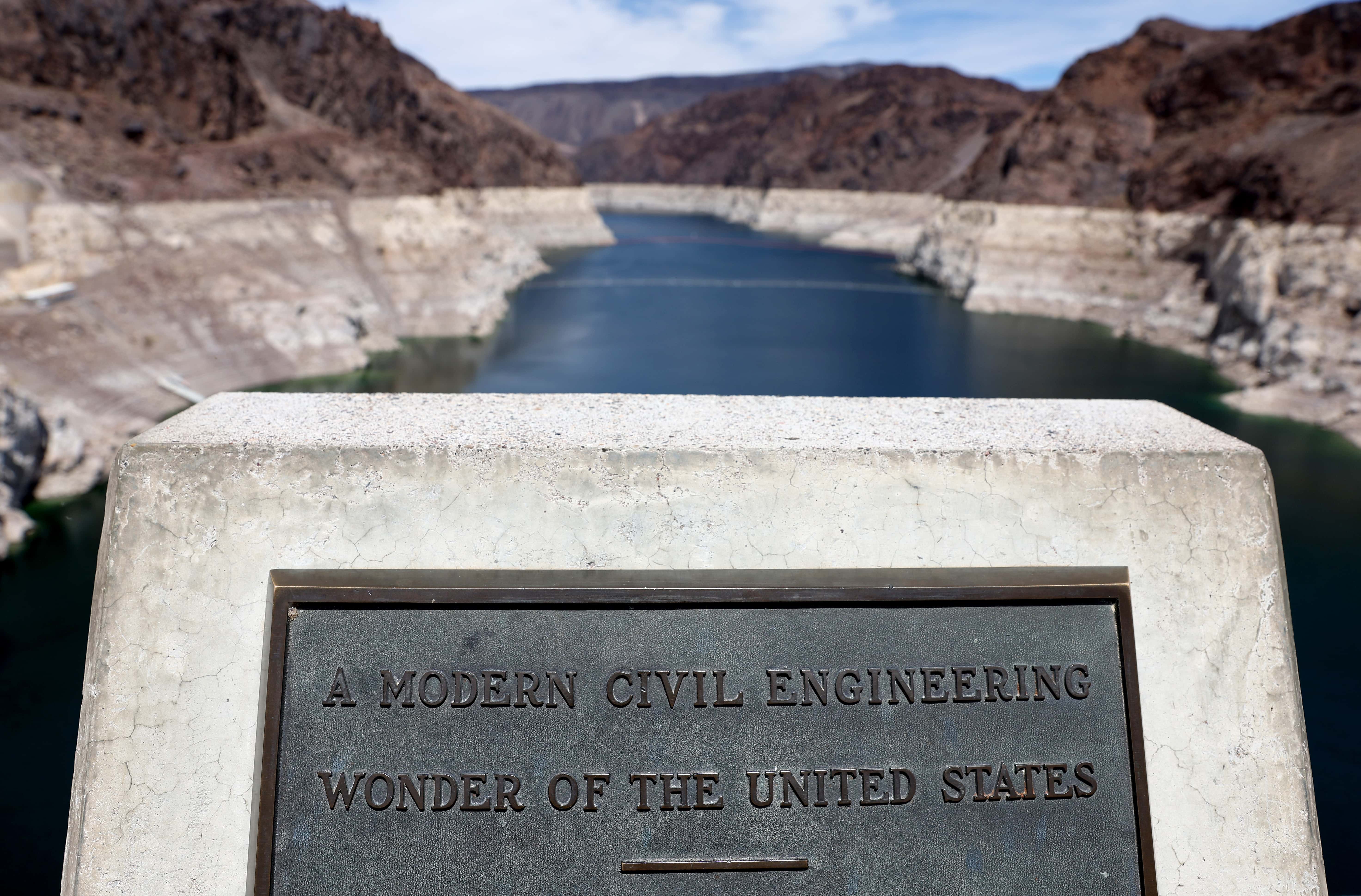 A plaque is displayed at the Nevada-Arizona state line on the Hoover Dam, with Lake Mead in the background, on May 10, 2022 in the Lake Mead National Recreation Area, Nevada. The U.S. Bureau of Reclamation reported that Lake Mead, North America's largest artificial reservoir, has dropped to about 1,052 feet above sea level, the lowest it's been since being filled in 1937 after the construction of the Hoover Dam. Two sets of human remains have been discovered recently as the lake continues to recede. The declining water levels are a result of a climate change-fueled megadrought coupled with increased water demands in the Southwestern United States.